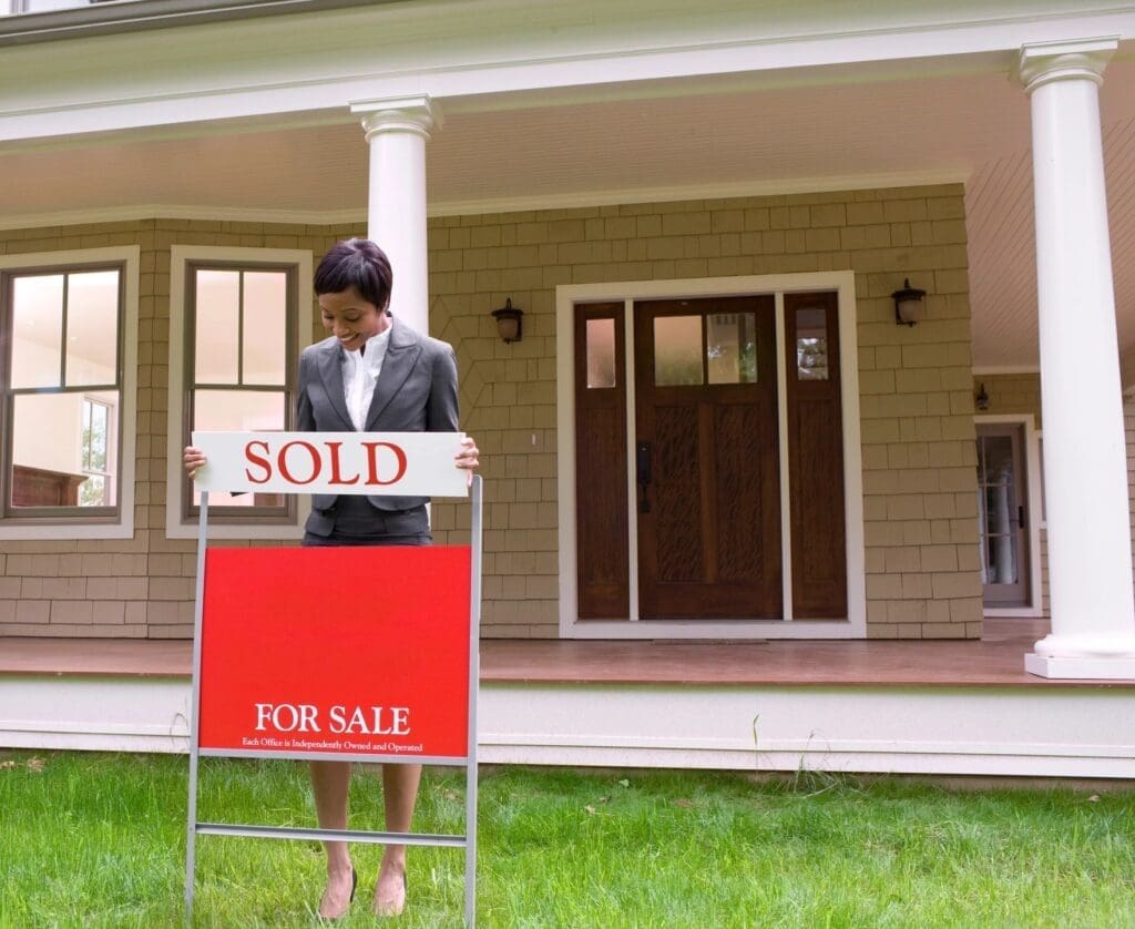 A woman standing in front of a house with a sold sign.