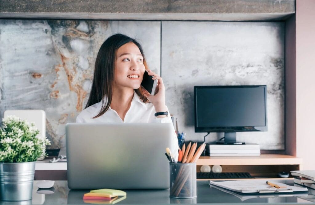 A woman sitting at her desk talking on the phone.