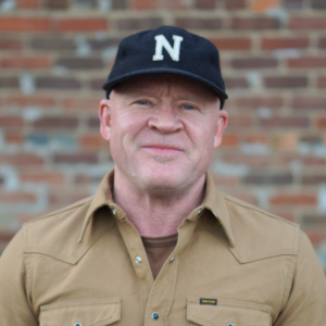 A man wearing a hat and brown shirt.